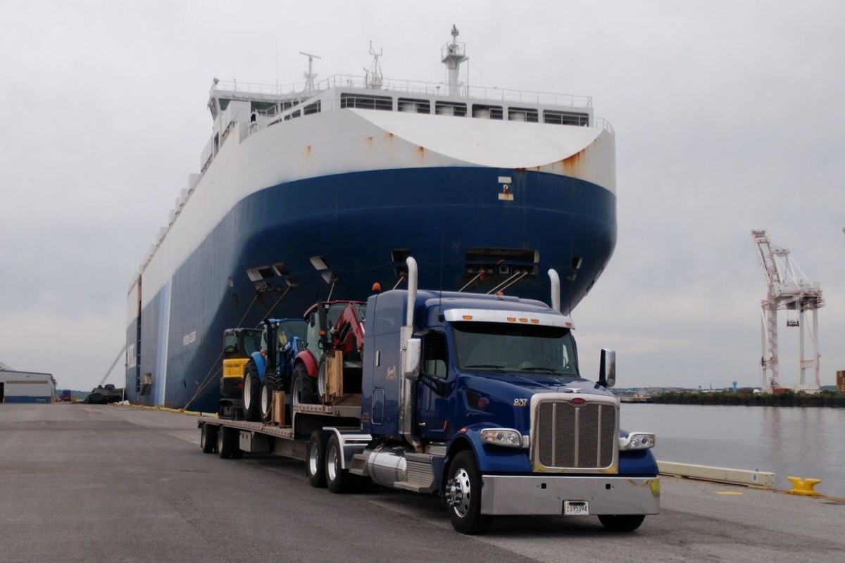 Boat secured on a trailer alongside a transport truck